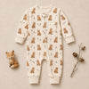 A baby long-sleeve footless one-piece sleeper in cream with an all-over fox print, laid flat on a beige background with a small wooden fox figurine and dried acorns as props.