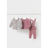 Three baby clothing items hanging on white hangers from a metal rail against a light gray wall: a long-sleeve floral cardigan, a dusty pink cable-knit cardigan, and a matching dusty pink overalls set.