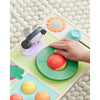Child's hand interacting with a colorful puzzle toy on a textured surface