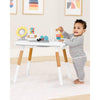 Child playing with a toy table in a room with colorful abstract art on the wall.